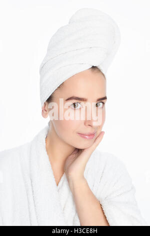 Pretty young woman with white towel on her head and light makeup, studio portrait Stock Photo