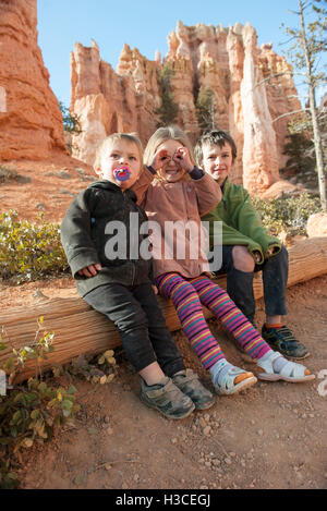 Children sitting on tree trunk at Bryce Canyon National Park, Utah, USA Stock Photo