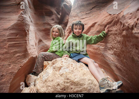 Children sitting on rock formation in Utah, USA Stock Photo
