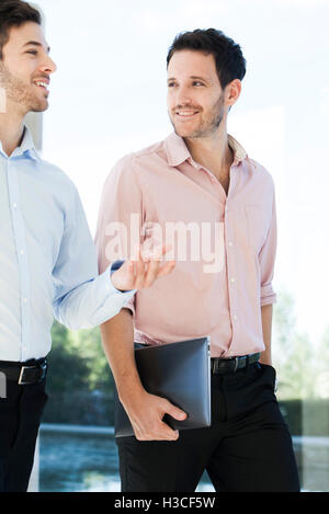 Business colleagues chatting while walking together Stock Photo