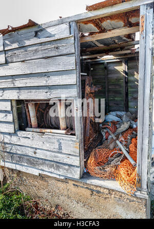 Abandoned fisherman's hut with winch machinery and nets on the beach at Dunwich, a village on the Suffolk coast, East Anglia, UK Stock Photo