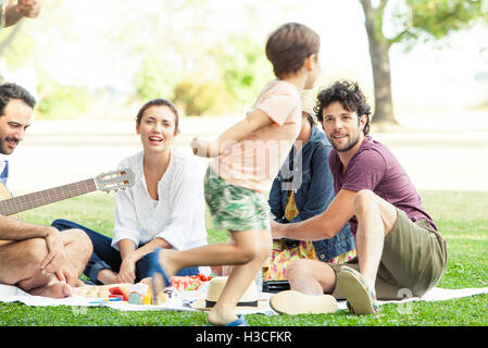 Family enjoying picnic in park, boy running around Stock Photo