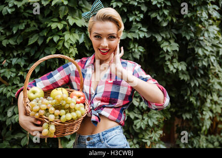 Portrait of happy attracttive pin-up girl with basket of fresh fruits Stock Photo