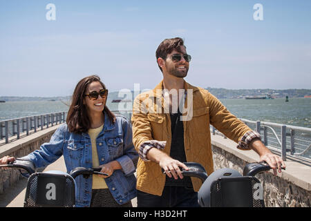 Happy couple with bicycles walking at observation point against clear sky Stock Photo