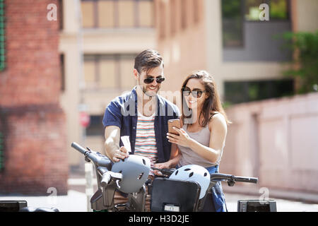 Young couple using smart phone while standing with bicycles Stock Photo
