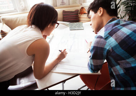 Overhead view of couple examining blueprint at home Stock Photo