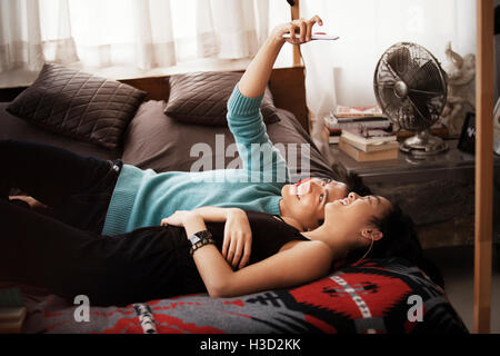 Happy couple taking selfie while lying on bed at home Stock Photo