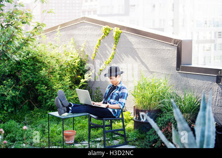 Man using laptop while sitting with feet up on table at terrace Stock Photo
