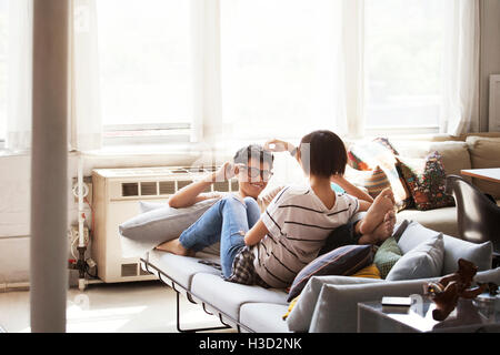 Happy couple talking while sitting on sofa at home Stock Photo