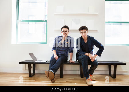 Portrait of confident businessmen sitting on bench in creative office Stock Photo