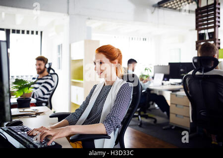 Happy businesswoman working on desktop computer in creative office Stock Photo