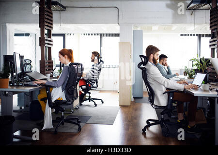Side view of business people working at computer desks in creative office Stock Photo