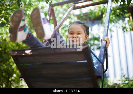 Portrait of happy girl playing on swing at backyard Stock Photo