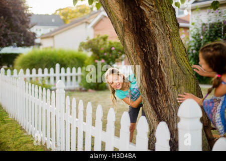 Happy sisters playing hide and seek in backyard Stock Photo