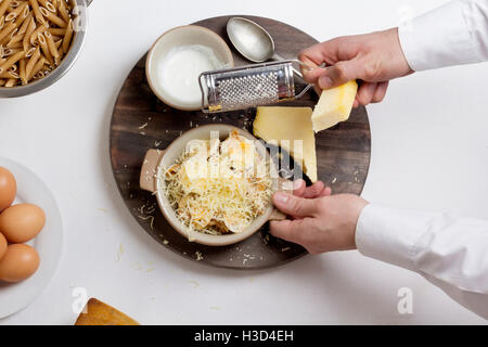 Overhead view of chef grating cheese on boiled eggs in bowl Stock Photo