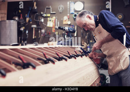 Senior man making boat in workshop Stock Photo