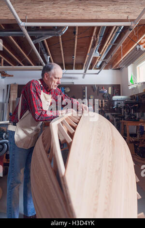 Senior man working on wooden boat in workshop Stock Photo