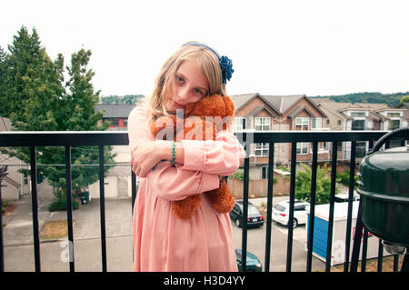 Portrait of girl holding teddy bear while standing at balcony Stock Photo