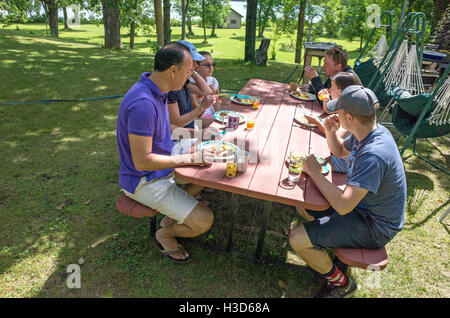 Family and guests having a lovely picnic table outdoor lunch. Clitherall Minnesota MN USA Stock Photo