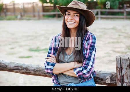 Portrait of cheerful attractive young woman cowgirl standing with arms crossed Stock Photo