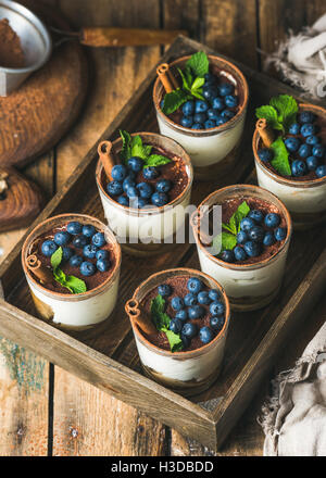 Tiramisu dessert with cinnamon, mint and blueberry in wooden tray Stock Photo