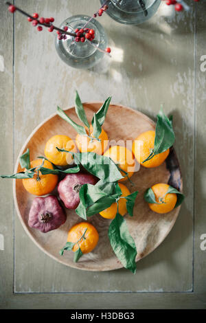 A wooden bowl of oranges, citrus fruits on a table top. Stock Photo