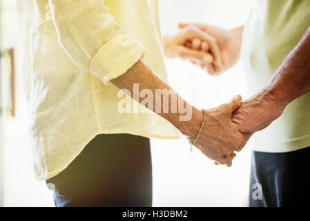 Close up of a senior couple holding hands, facing each other. Stock Photo