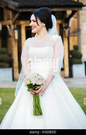 A bride in her wedding dress carrying a bouquet. Stock Photo