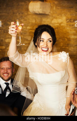 A bride on her wedding day raising her glass in a toast at the wedding party. Stock Photo