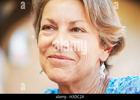 Smiling mature woman with red hair and earrings. Stock Photo