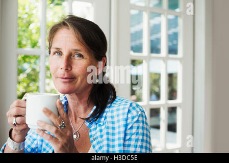 A woman drinking a mug of tea or coffee. Stock Photo