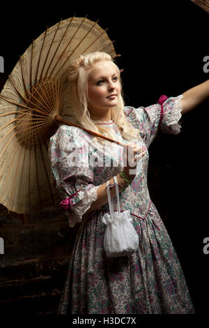 Young woman in vintage dress in attic with brolly Stock Photo