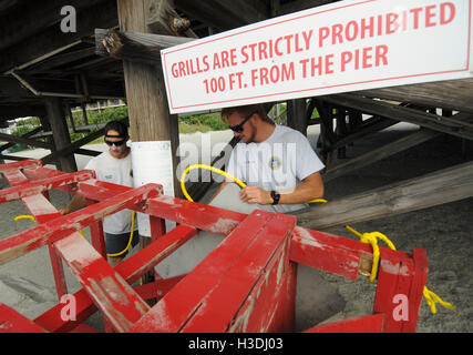 Florida, USA. 5th October, 2016. Brevard County lifeguards Morgan Rooney (left) and Zac James tie a lifeguard chair to the pier at Cocoa Beach, Florida on October 5, 2016 as Hurricane Matthew heads north toward the east coast of Florida, possibly as a category 4 hurricane. The storm has killed 10 people in Caribbean countries and evacuations are underway in Florida and South Carolina. Credit:  Paul Hennessy/Alamy Live News Stock Photo