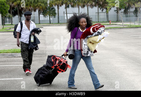 Weston, FL, USA. 6th Oct, 2016. fl-matthew-shelter-ta-4-ng : (right) Katongo Chama with her father, Sedelis Chama, walk with their things to the Red Cross Disaster Shelter at Falcon Cove Middle School in Weston Thursday as the effects of Hurricane Matthew begin to be felt. Chama live in a mobile home in Davie and itÃ¢â‚¬â„¢s their first hurricane, so she decided it was safer to ride out the storm at a shelter. Hurricane Matthew returned to Category 4 strength Thursday morning and could be producing ''extremely dangerous'' sustained winds of 145 mph by the time it approaches South Flor Stock Photo