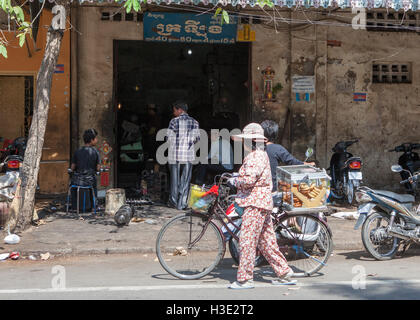 Woman pushing her bike selling bread in the streets of Phnom Penh,Cambodia. Stock Photo