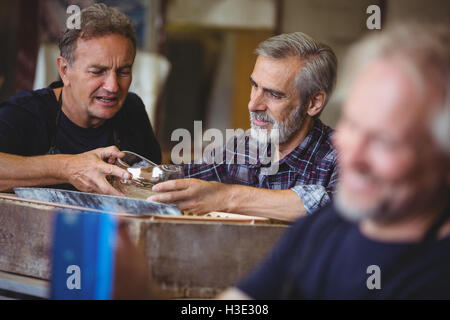 Glassblower and a colleague looking glassware Stock Photo