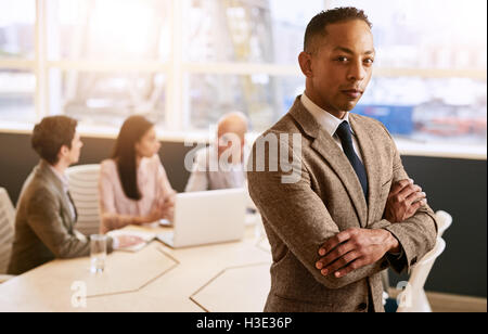 Businessman standing in front of his employees with crossed arms Stock Photo