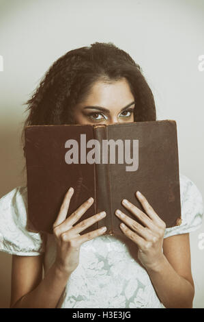 Young woman hiding face with an open book Stock Photo