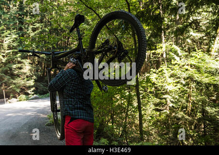 Male cyclist carrying mountain bike while walking Stock Photo