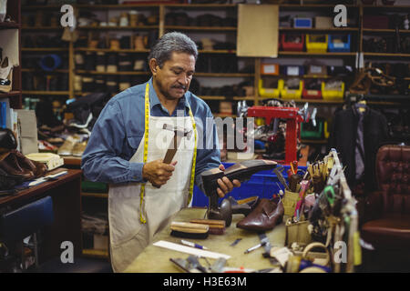 Shoemaker hammering on a shoe Stock Photo