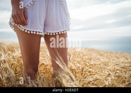 Mid section of woman standing in wheat field Stock Photo
