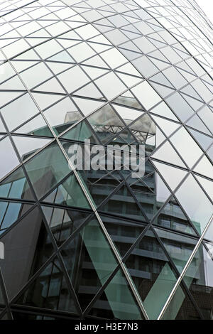 A view of the gherkin building at 30 St Mary Axe with Bevis Marks building reflection in London UK  KATHY DEWITT Stock Photo