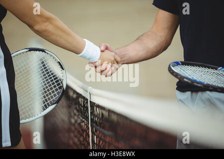 Mid section of tennis players shaking hands in the court Stock Photo
