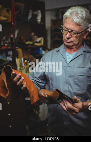 Shoemaker examining a boot and piece of material Stock Photo