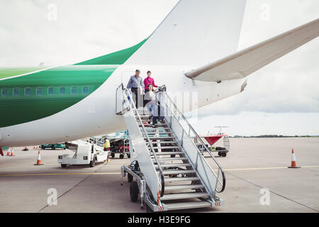 Passengers exit airplane down stairs Stock Photo