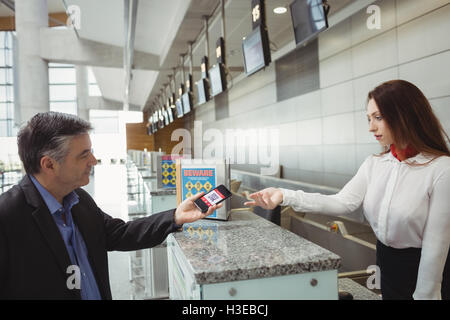 Businessman showing mobile boarding pass to airline check-in attendant Stock Photo