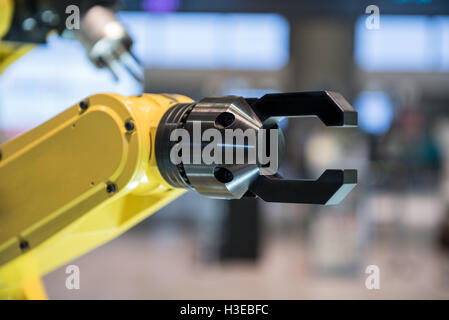 A yellow robotic arm isolated on a blurry background Stock Photo