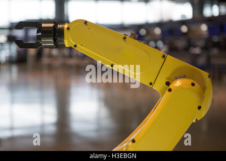 A yellow robotic arm isolated on a blurry background Stock Photo