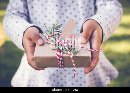 kid holding eco gift box with brown tag, holidays toning background Stock Photo