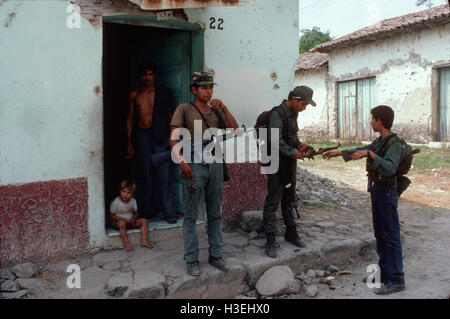 TENANCINGO,  EL SALVADOR, MARCH 1984: - Within the FPL Guerrilla's Zones of Control.  Guerrilla fighter outside a shop that still functions in the partly ruined town of Tenancingo. Stock Photo